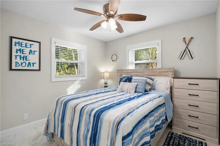 Bedroom with a ceiling fan and light marble finish floors