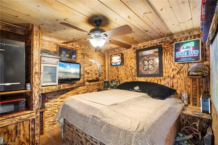 Bedroom with wooden walls, hardwood / wood-style flooring, ceiling fan, and wooden ceiling