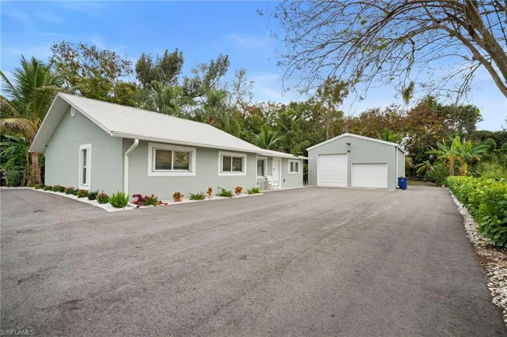 Ranch-style home featuring an outbuilding, a garage, stucco siding, and a metal roof