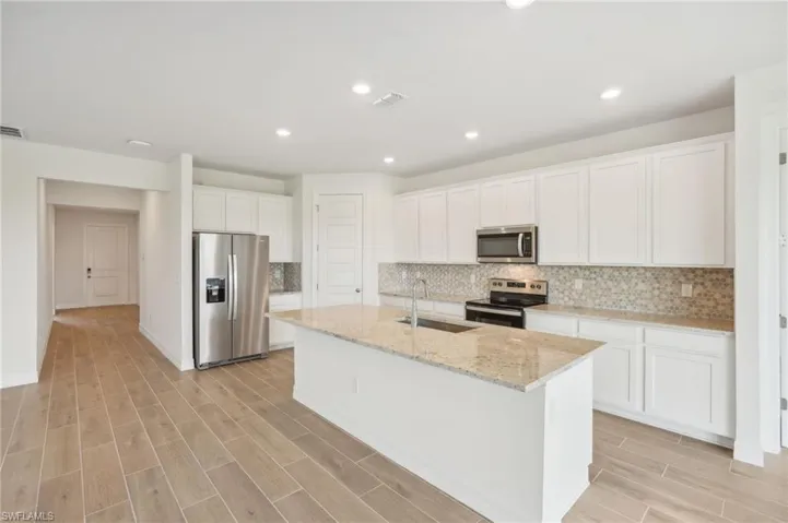 Kitchen with white cabinets, sink, a center island with sink, stainless steel appliances, and light hardwood / wood-style floors