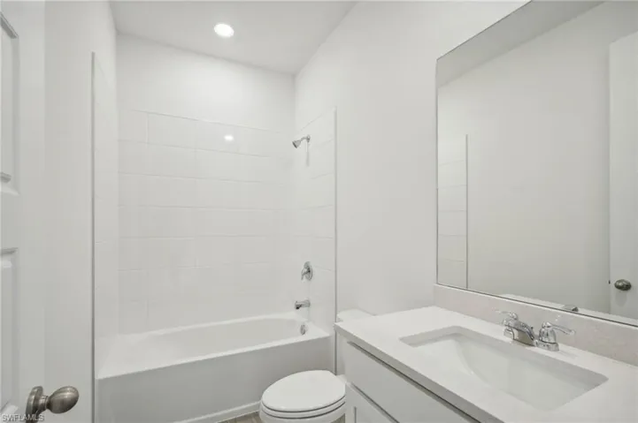 Full bathroom with tiled shower / bath combo, vanity, and toilet