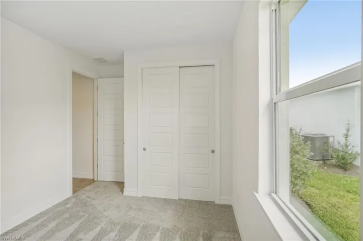 Unfurnished bedroom with light carpet and a closet