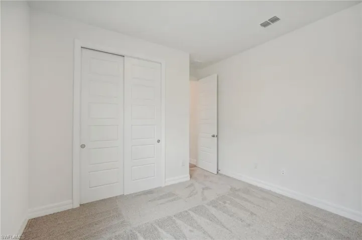 Unfurnished bedroom with light colored carpet and a closet