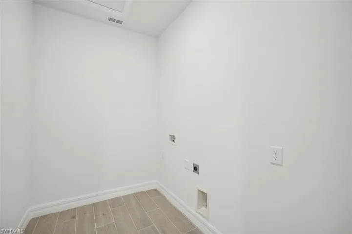 Clothes washing area with light wood-type flooring, hookup for an electric dryer, and hookup for a washing machine