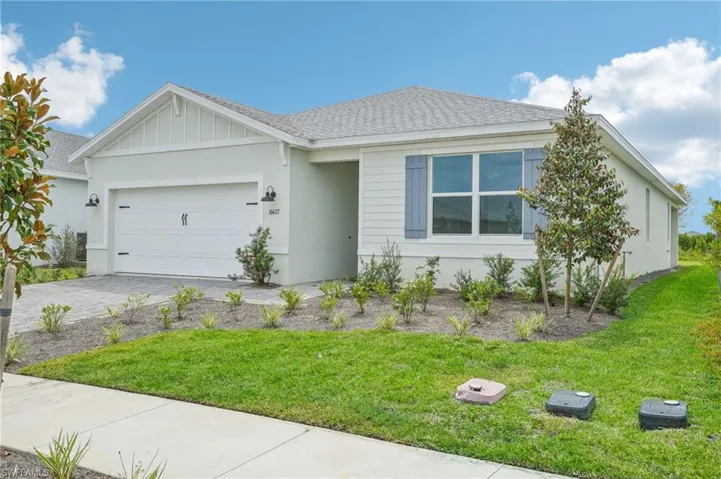 View of front facade featuring a garage and a front lawn