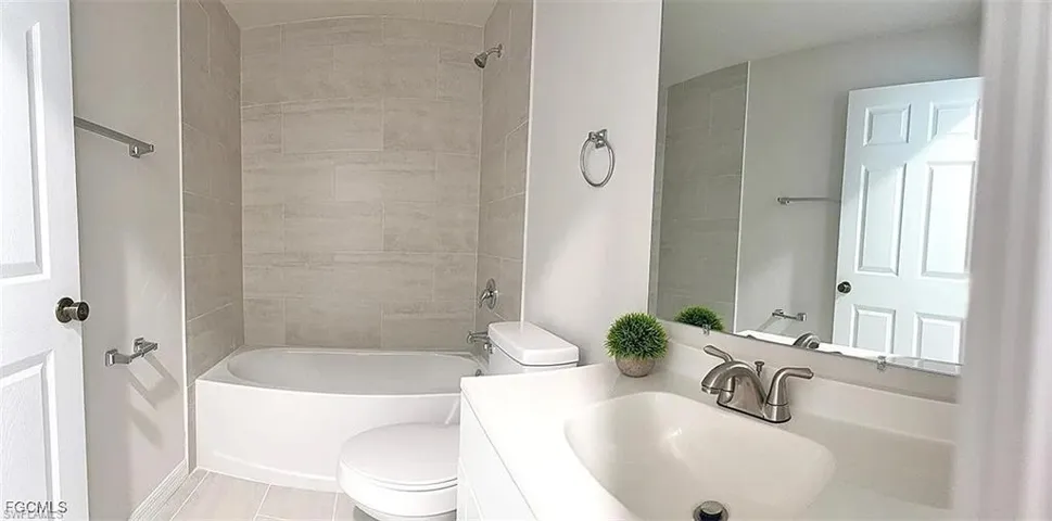 Bathroom featuring a white vanity with an integrated sink, brushed nickel faucet, and a large wall-mounted mirror