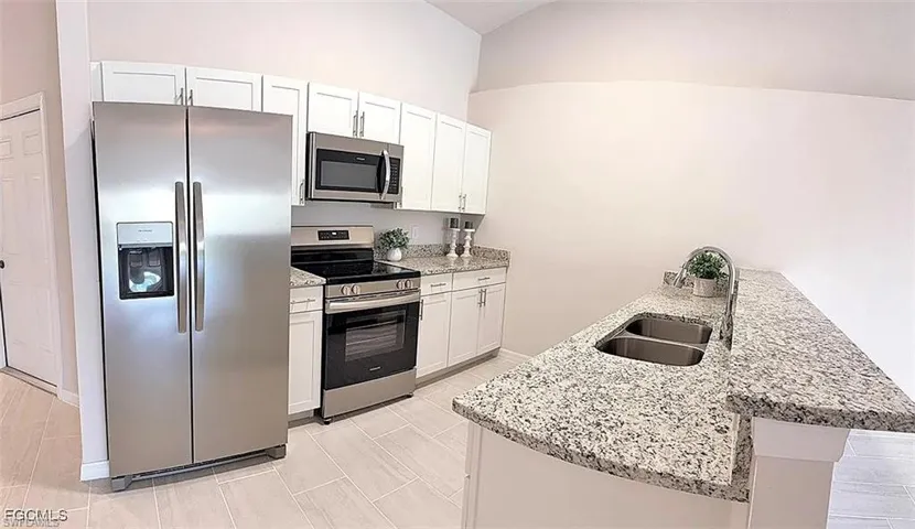 Kitchen featuring stainless steel appliances, white cabinetry, granite countertops, and light-toned tile flooring