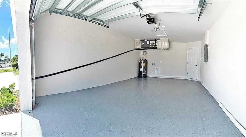 Attached garage featuring an epoxy-coated floor, automatic garage door opener, textured walls, and a utility access door
