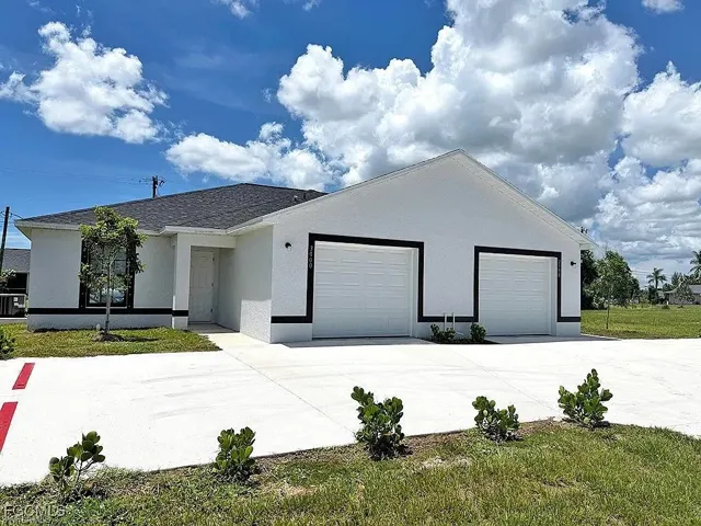 Contemporary white stucco exterior with black trim accents, a dark shingle roof, dual garage doors, a concrete driveway, and a small front yard with newly planted landscaping