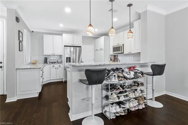 Kitchen with appliances with stainless steel finishes, kitchen peninsula, and white cabinets