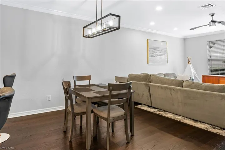 Dining room with crown molding, dark hardwood / wood-style floors, and ceiling fan