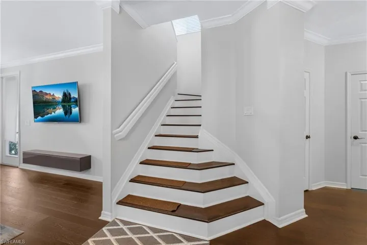 Stairs featuring hardwood / wood-style floors and crown molding