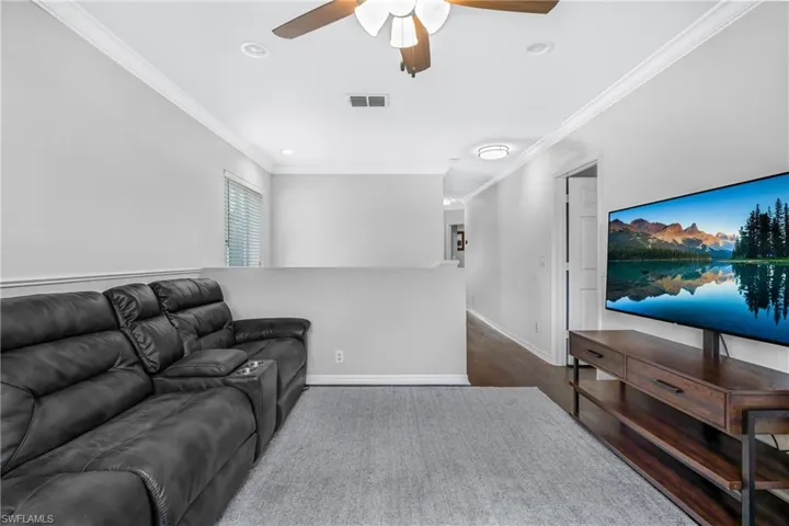 Living room featuring dark hardwood / wood-style flooring, crown molding, and ceiling fan