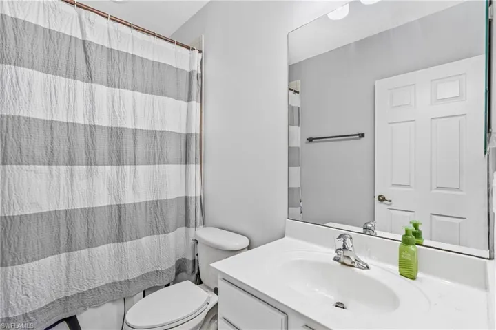 Bathroom featuring vanity, curtained shower, and toilet