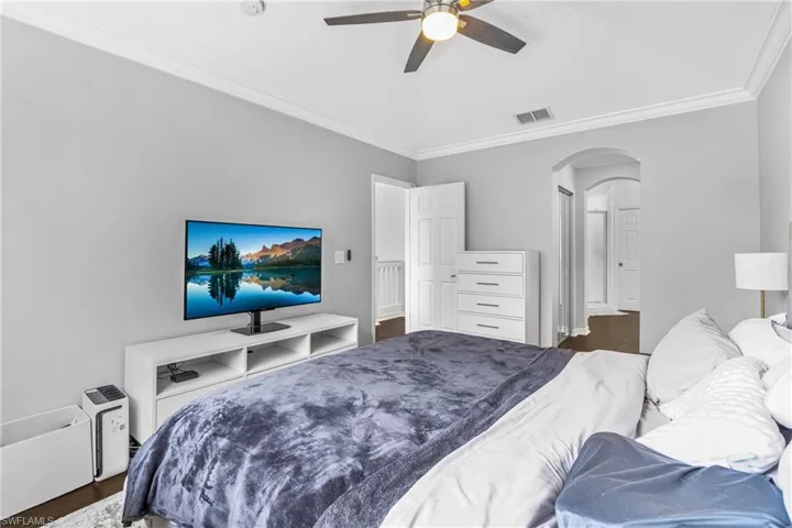 Bedroom with crown molding, ceiling fan, and dark hardwood / wood-style floors