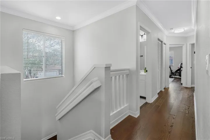 Corridor featuring dark wood-type flooring and ornamental molding