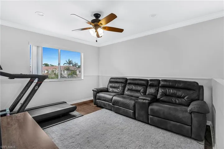 Living room with crown molding, ceiling fan, and wood-type flooring