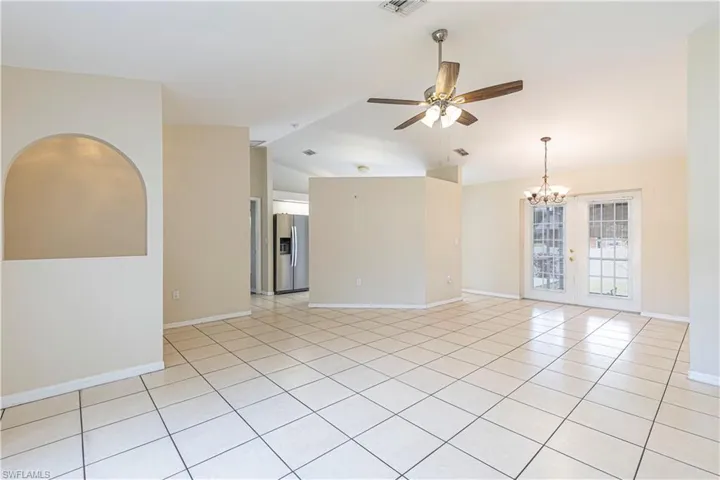 Spare room with lofted ceiling, a ceiling fan, light tile patterned floors, a chandelier, and french doors