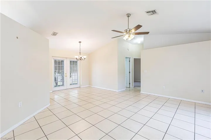 Unfurnished room featuring ceiling fan, a chandelier, light tile patterned floors, french doors, and high vaulted ceiling