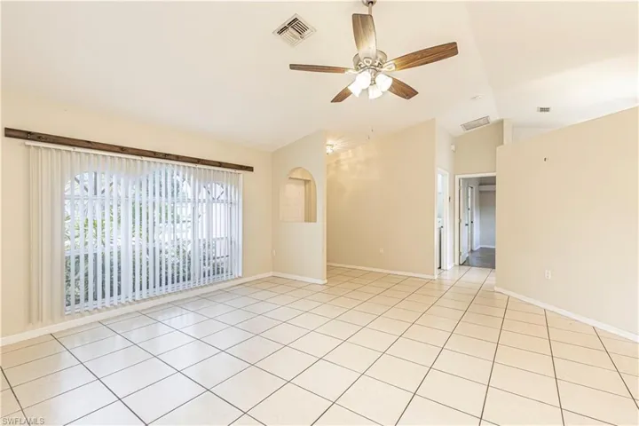 Unfurnished room with lofted ceiling, ceiling fan, and light tile patterned floors