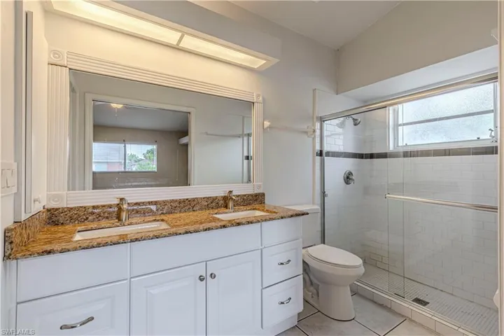 Full bathroom featuring plenty of natural light, double vanity, a shower stall, and tile patterned floors