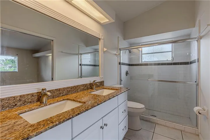 Full bathroom with a stall shower, double vanity, tile patterned flooring, and healthy amount of natural light