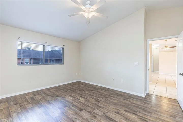 Empty room with vaulted ceiling, a ceiling fan, and wood finished floors