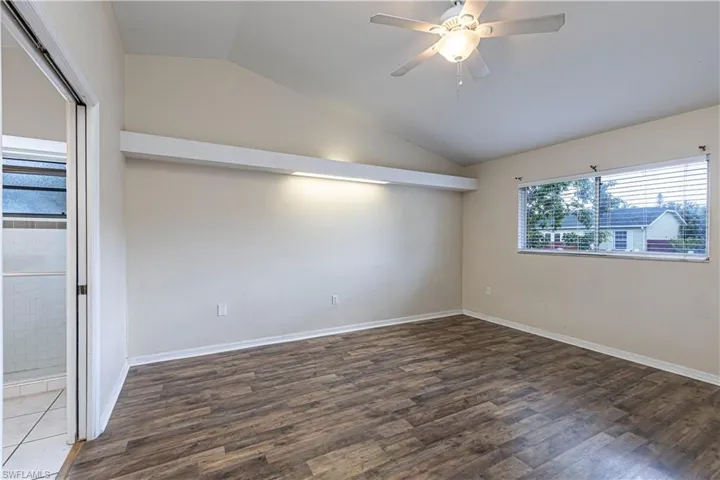 Unfurnished room with lofted ceiling, wood finished floors, and a ceiling fan