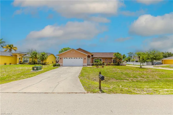 View of front of home with stucco siding, an attached garage, driveway, and a front yard