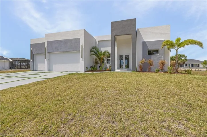 Contemporary house with driveway, a garage, a front lawn, stucco siding, and french doors