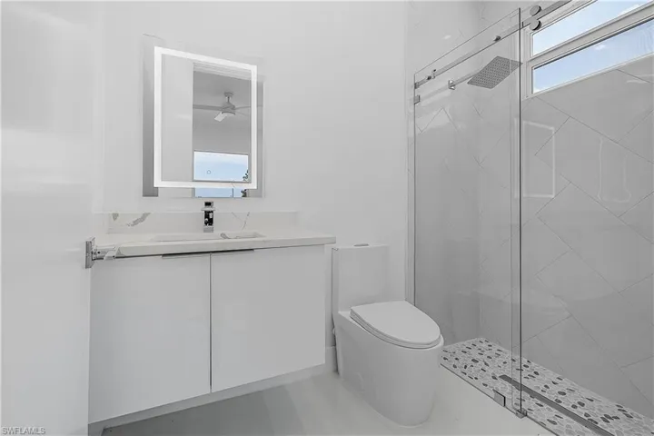 Bathroom featuring vanity, toilet, and a shower stall