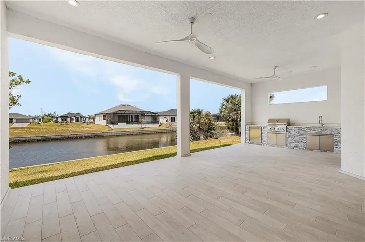 View of patio featuring a water view, outdoor kitchen, and ceiling fans
