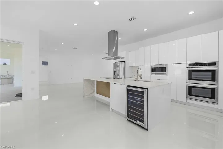 Kitchen featuring white cabinets, modern cabinets, wine cooler, stainless steel appliances, and island range hood