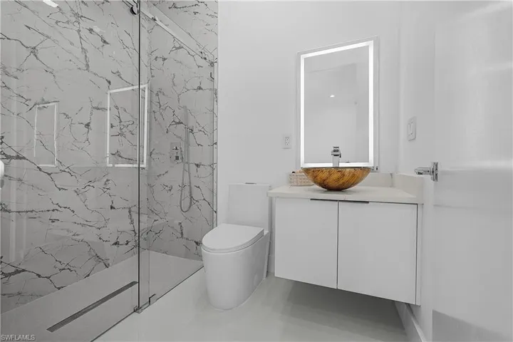 Bathroom with toilet, vanity, and shower
