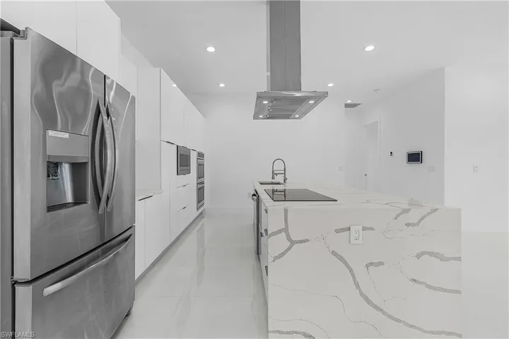 Kitchen with a sink, modern cabinets, stainless steel refrigerator with ice dispenser, and black electric stovetop