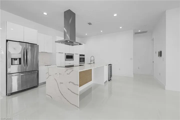 Kitchen with white cabinetry, modern cabinets, beverage cooler, stainless steel appliances, and island exhaust hood