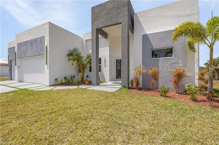 Contemporary house featuring stucco siding, an attached garage, concrete driveway, and a front yard