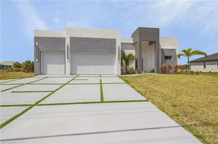 Contemporary house with a garage, concrete driveway, stucco siding, and a front lawn