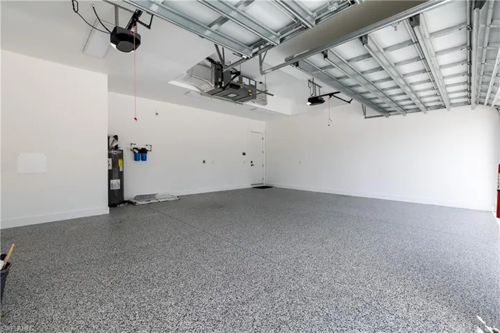 Garage featuring water heater, baseboards, and a garage door opener
