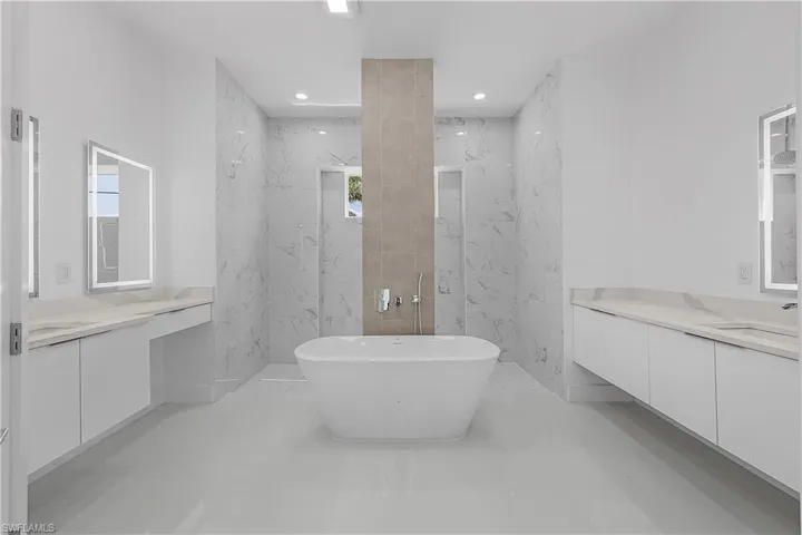 Primary bathroom featuring a freestanding tub, recessed lighting, vanity, and a shower