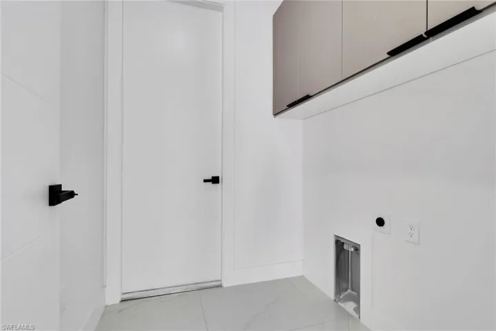 Laundry room with cabinet space, hookup for an electric dryer, and light marble finish floors