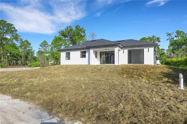 Back of house with stucco siding and a yard