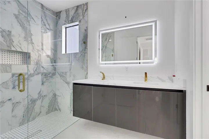 Bathroom with double vanity and a marble finish shower