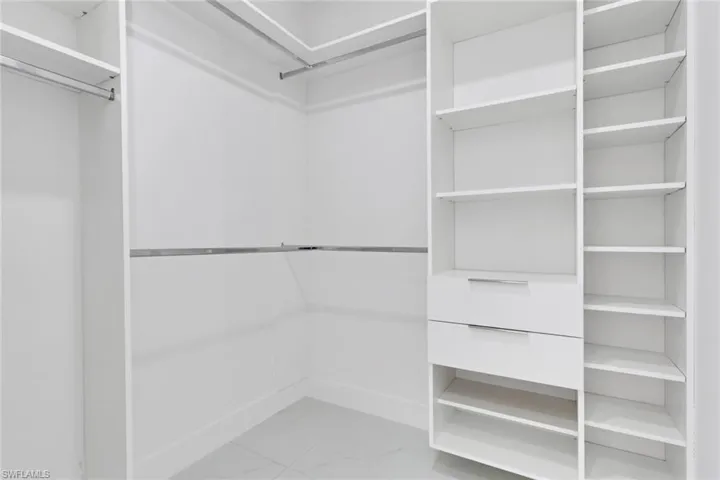 Walk in closet featuring light marble finish floors