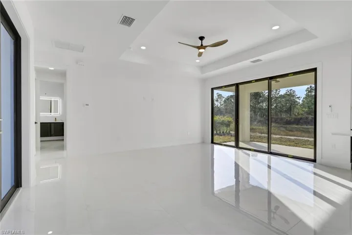 Empty room featuring a ceiling fan, recessed lighting, and a tray ceiling