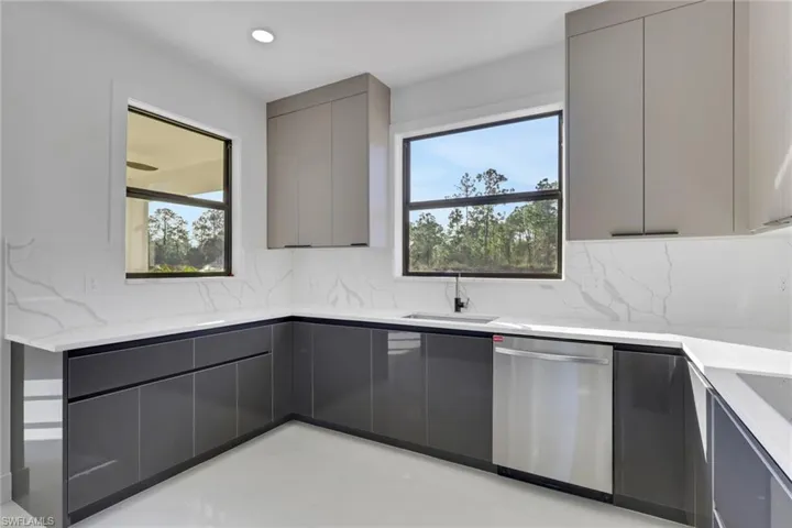 Kitchen with gray cabinetry, modern cabinets, dishwasher, decorative backsplash, and light stone counters