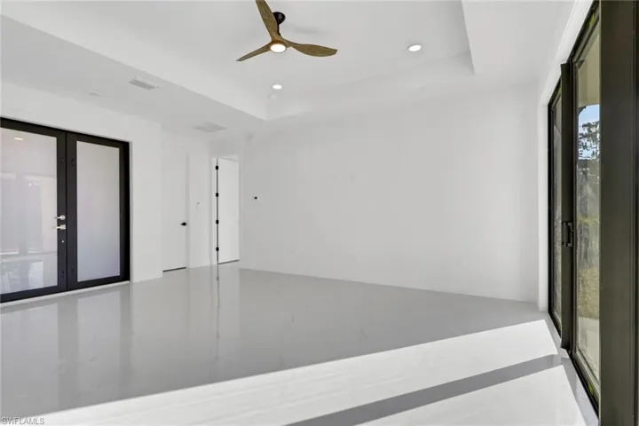 Unfurnished room with a ceiling fan, a raised ceiling, and recessed lighting