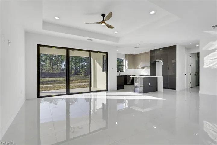 Unfurnished living room featuring a ceiling fan, a raised ceiling, and recessed lighting