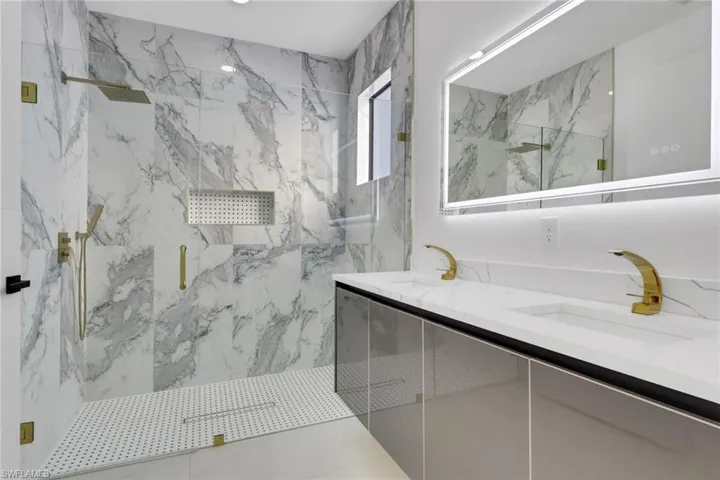 Bathroom featuring a marble finish shower and double vanity