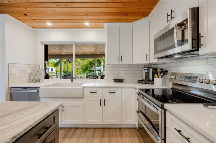 Kitchen featuring stainless steel appliances, light hardwood / wood-style floors, backsplash, and wooden ceiling